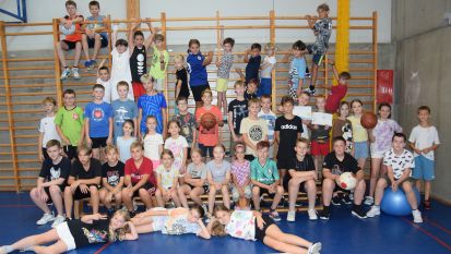 Grupa dzieci w sali gimnastycznej, na tle drabinek
